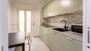 Une cuisine moderne avec des meubles de couleur vert clair, un évier noir et un four à micro-ondes.