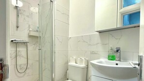 Ein Badezimmer mit Dusche, Toilette, Waschbecken und Schrank.
