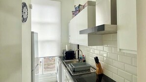 Eine Küche mit weißen Schränken, einer schwarzen Arbeitsplatte, einem eingebauten Backofen und einem Fenster.