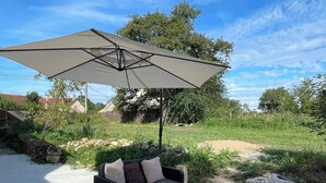 An outdoor patio with a sofa set and a large umbrella. - Gite "Le Chatel (Prissac)