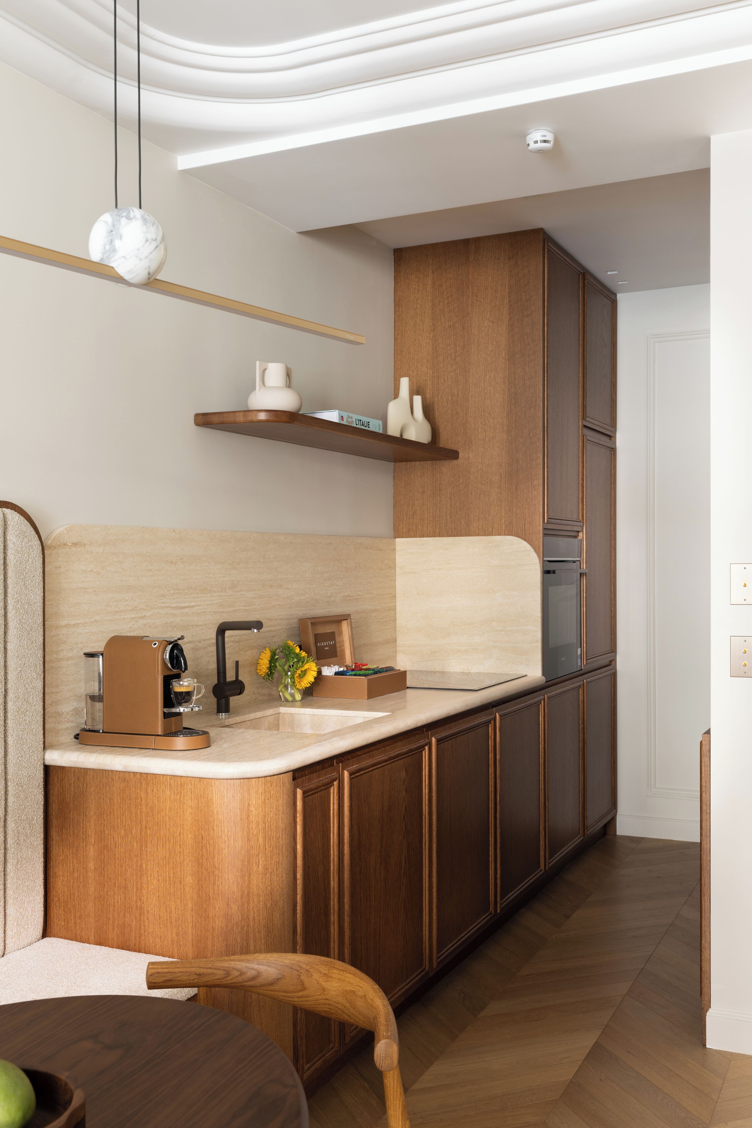 Una cocina moderna con armarios de madera, horno empotrado y cafetera.