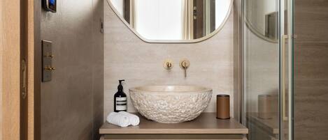 A modern bathroom with a wooden vanity, a large oval mirror, and a glass shower enclosure.