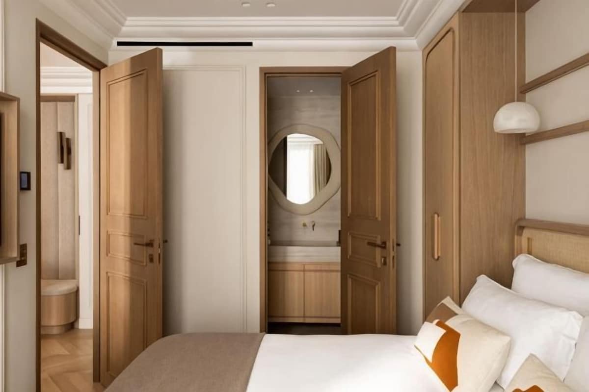 A bedroom with a large bed, wooden wardrobe, and a mirror.