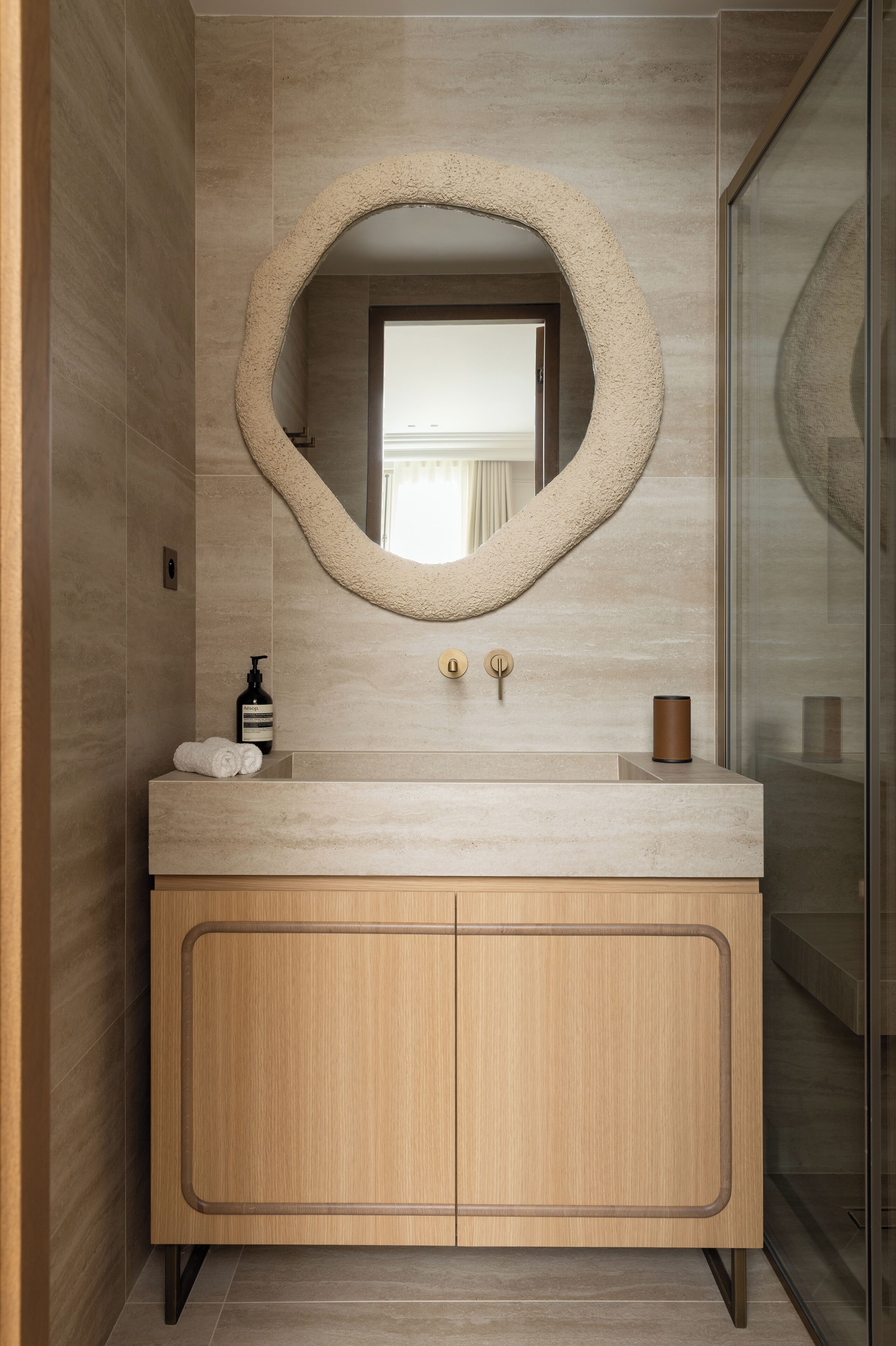 A bathroom with a large mirror, a wooden vanity, and a glass shower enclosure.