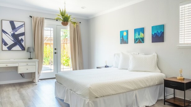 Une chambre à coucher avec un grand lit, un bureau et une fenêtre avec des rideaux.