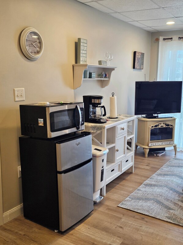 A compact kitchen with a refrigerator, microwave, coffee maker, and a television on a stand. - Guest Suite In Hull With Bedroom, Living Room, Dining Area, Full Bath, arking (Hull)