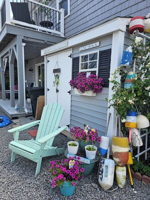 A quaint cottage with a porch, a green chair, and various potted plants. - Guest Suite In Hull With Bedroom, Living Room, Dining Area, Full Bath, arking (Hull)
