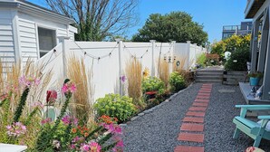 A garden pathway with stepping stones leading to a bench, surrounded by various plants and flowers.