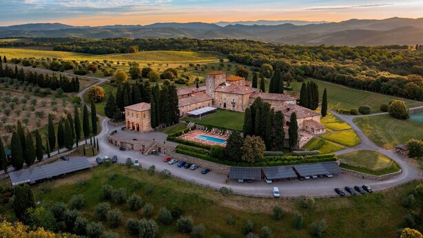 Vista aérea de una finca histórica con un patio central, varios edificios y jardines ajardinados circundantes.