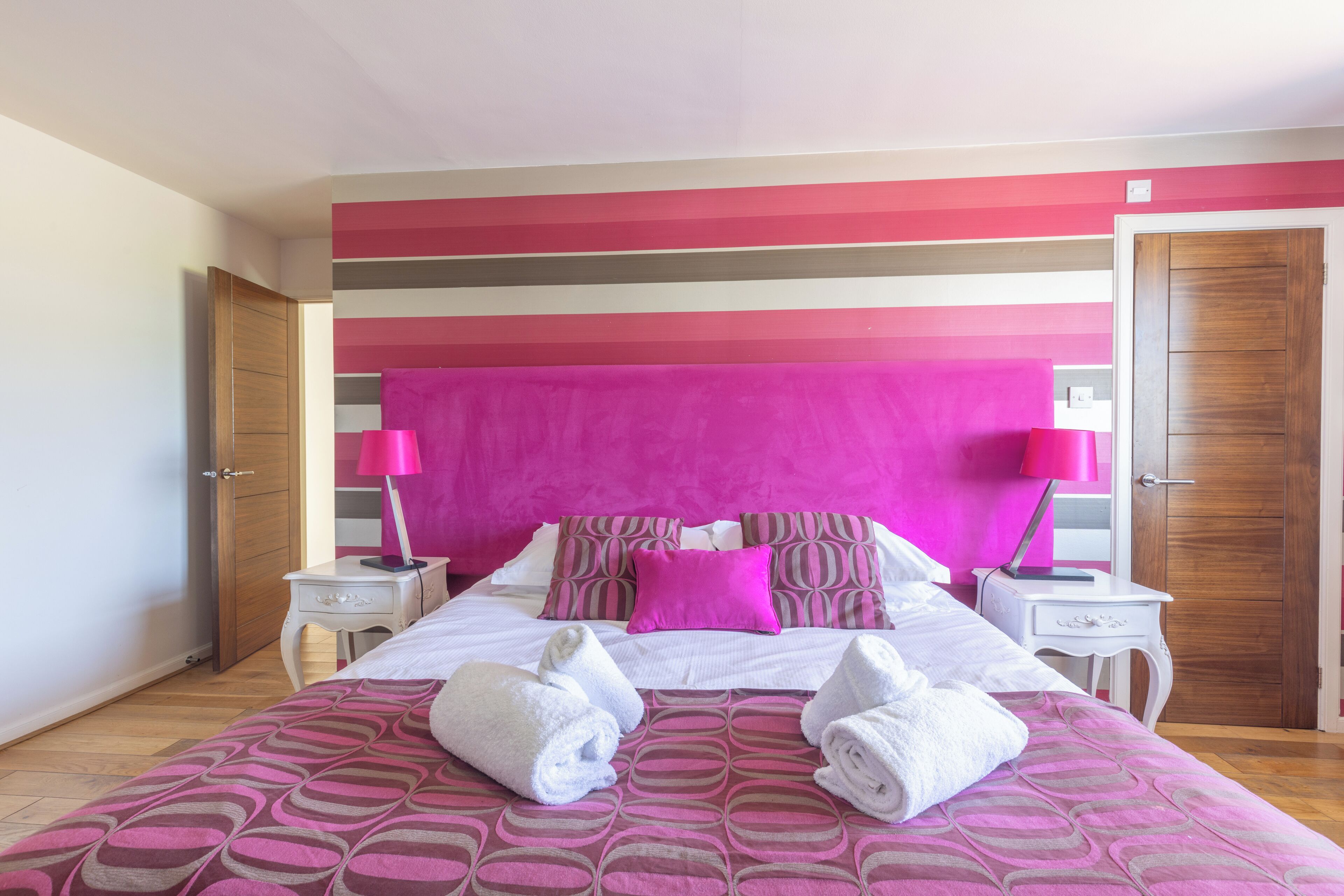 A hotel room with a bed, two bedside tables, a wardrobe, and a door.