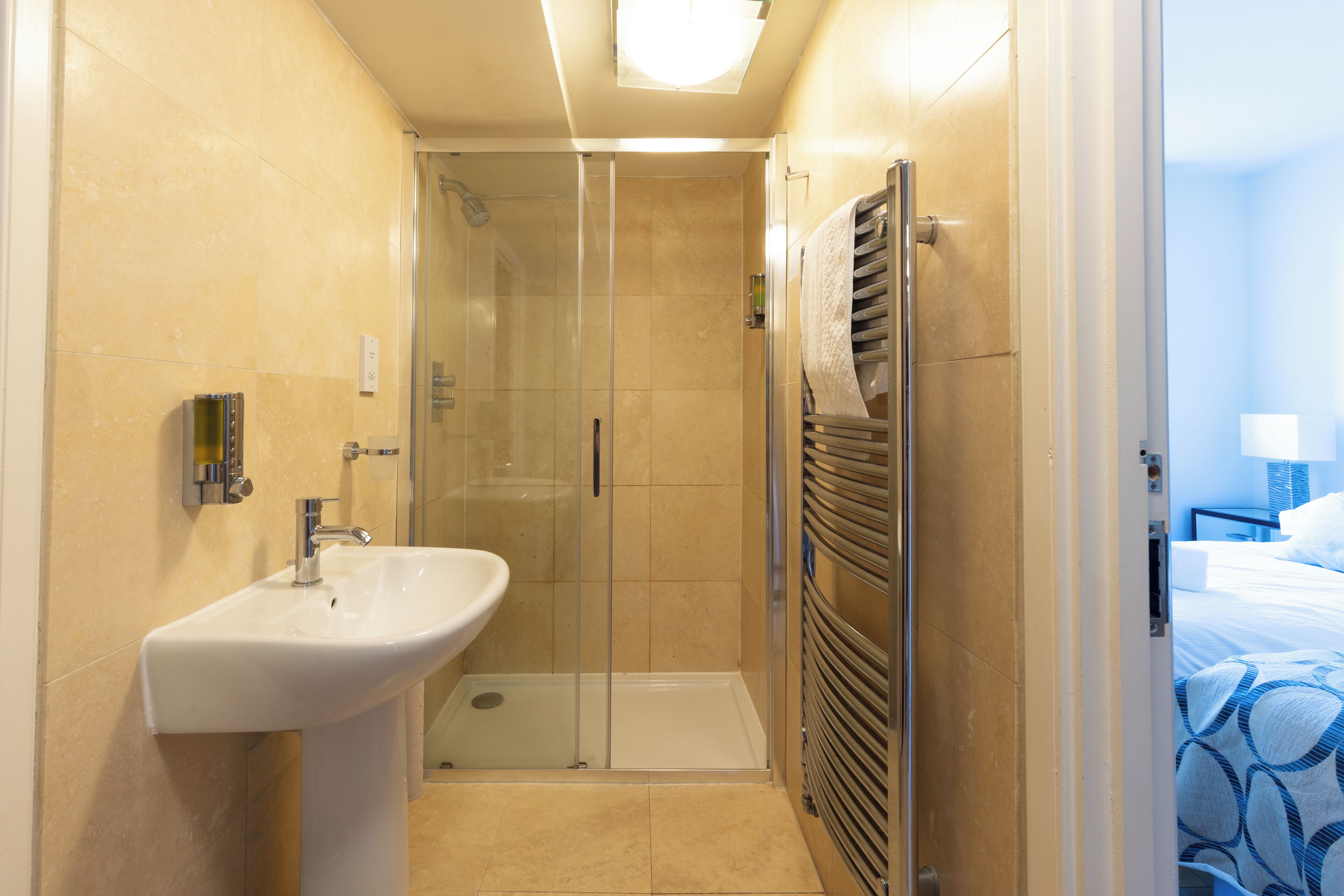 Un baño con ducha de vidrio, lavamanos blanco y toallero.