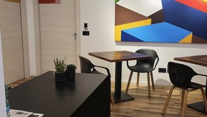 Un espace de bureau moderne avec deux bureaux en bois, des chaises noires et un grand tableau abstrait accroché au mur.