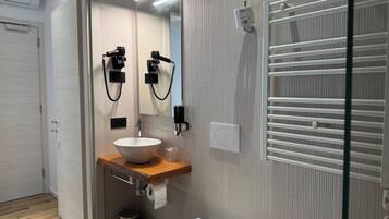 A modern bathroom with a wooden vanity, a white sink, a mirror, a towel rack, and a toilet.