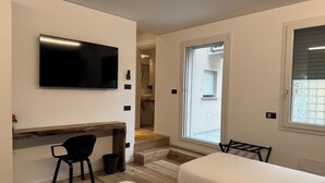 A modern bedroom with a TV, a desk, two beds, and a window. - Room 4 Sofia (Orzinuovi)