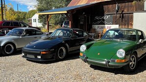 A vintage car collection parked in front of a rustic building with a sign reading "5680".