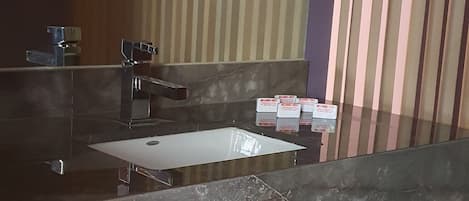 Un baño con un espejo grande, un lavabo e inodoro.