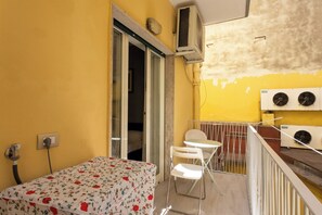 A small room with a bed, a chair, a table, and an air conditioning unit. - Ninetta a Foria - One Bedroom Apartment, Sleeps 4 (Naples)