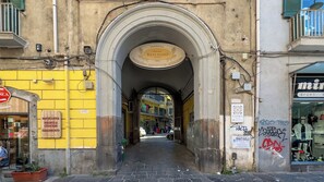 A narrow street with an archway leading to a building with a sign reading "PANIFICIO Antonio Rescigno." - Ninetta a Foria - One Bedroom Apartment, Sleeps 4 (Naples)
