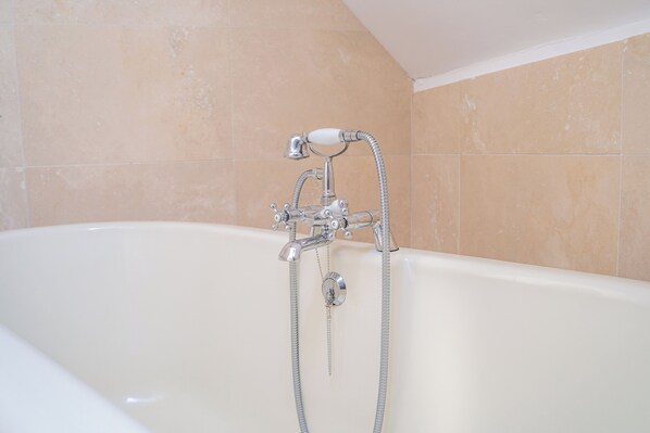 A bathroom with a bathtub, a shower, and a hand shower.