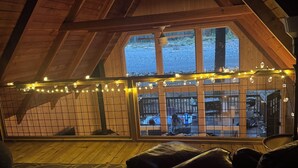 Een kamer op zolder met uitzicht op een garage en een groot raam.
