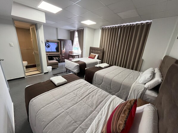 Une chambre d’hôtel avec deux lits, une télévision, un bureau et une salle de bain.