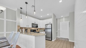 A modern kitchen with white cabinetry, stainless steel appliances, and a central island. - Beach & Golf Vacation 2 (Myrtle Beach)