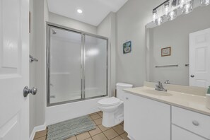 A bathroom with a glass-enclosed shower, a toilet, a sink with a mirror, and a towel rack. - Beach & Golf Vacation 2 (Myrtle Beach)