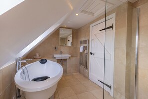 Un baño moderno con una bañera independiente, un lavabo, un espejo y una cabina de ducha de vidrio.