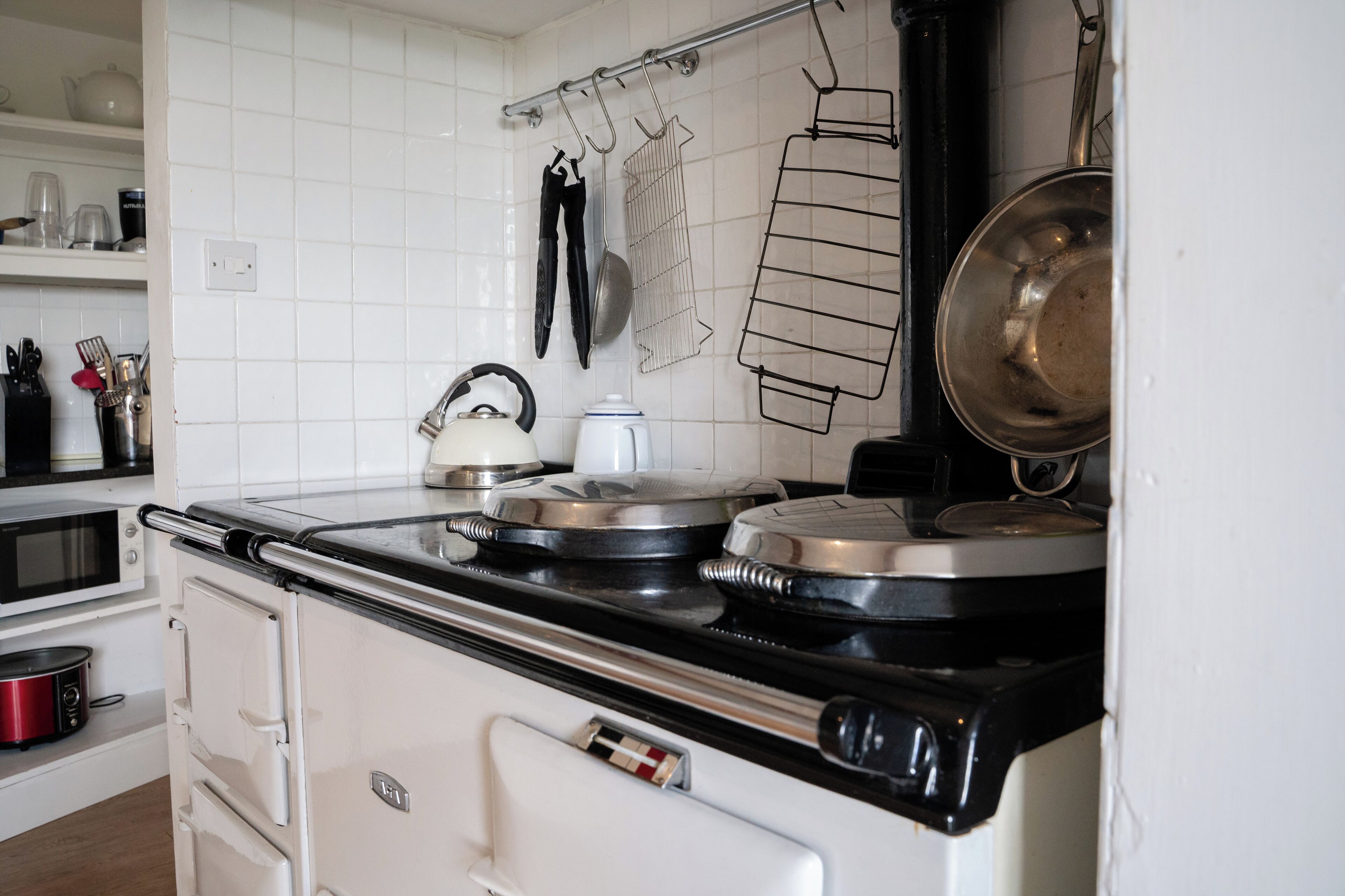 A kitchen with a stove, microwave, and various utensils.
