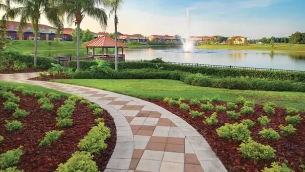 A landscaped pathway with a gazebo, a pond, and a fountain.