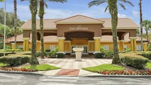 A hotel entrance with a sign reading "ENCANTADA CLUBHOUSE," surrounded by palm trees and well-maintained landscaping.