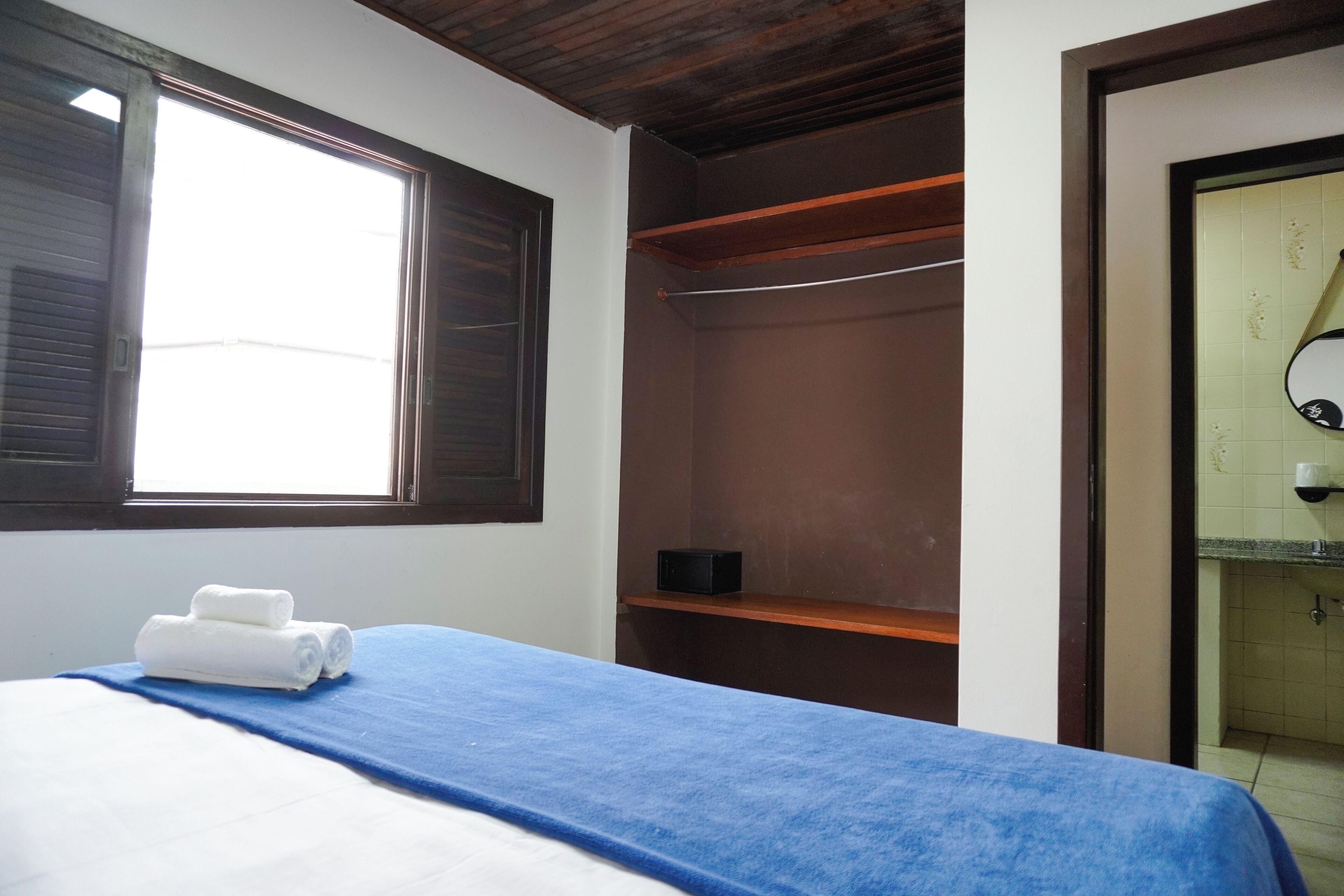 A hotel room with a bed, a window, a wardrobe, and a bathroom.