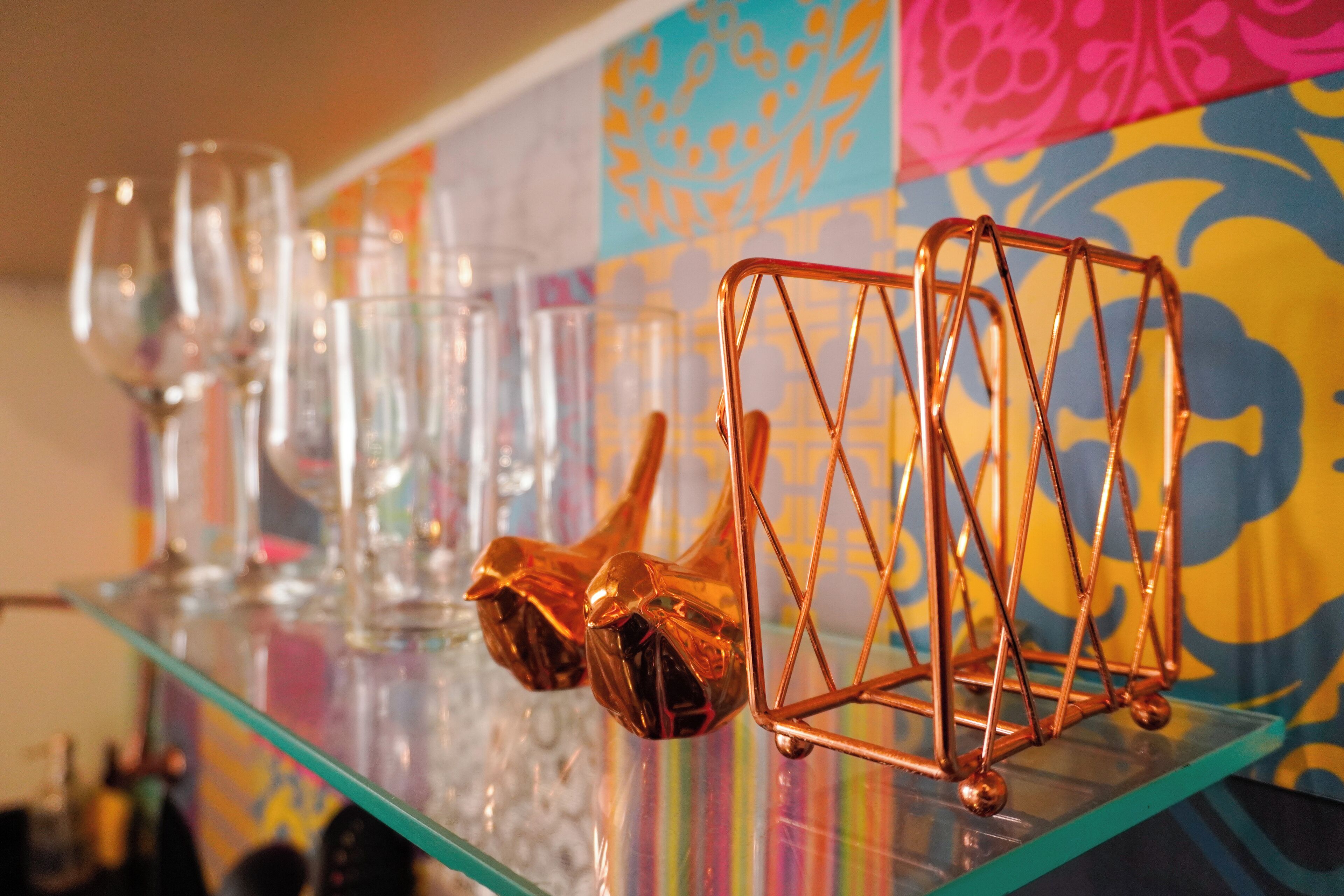 A bar area with a glass shelf displaying wine glasses and a copper decorative piece.