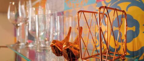 A bar area with a glass shelf displaying wine glasses and a copper decorative piece.