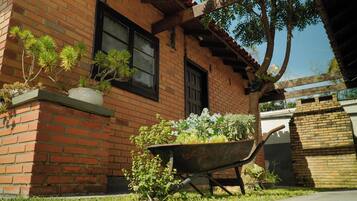 A brick building with a window and a wheelbarrow filled with plants.