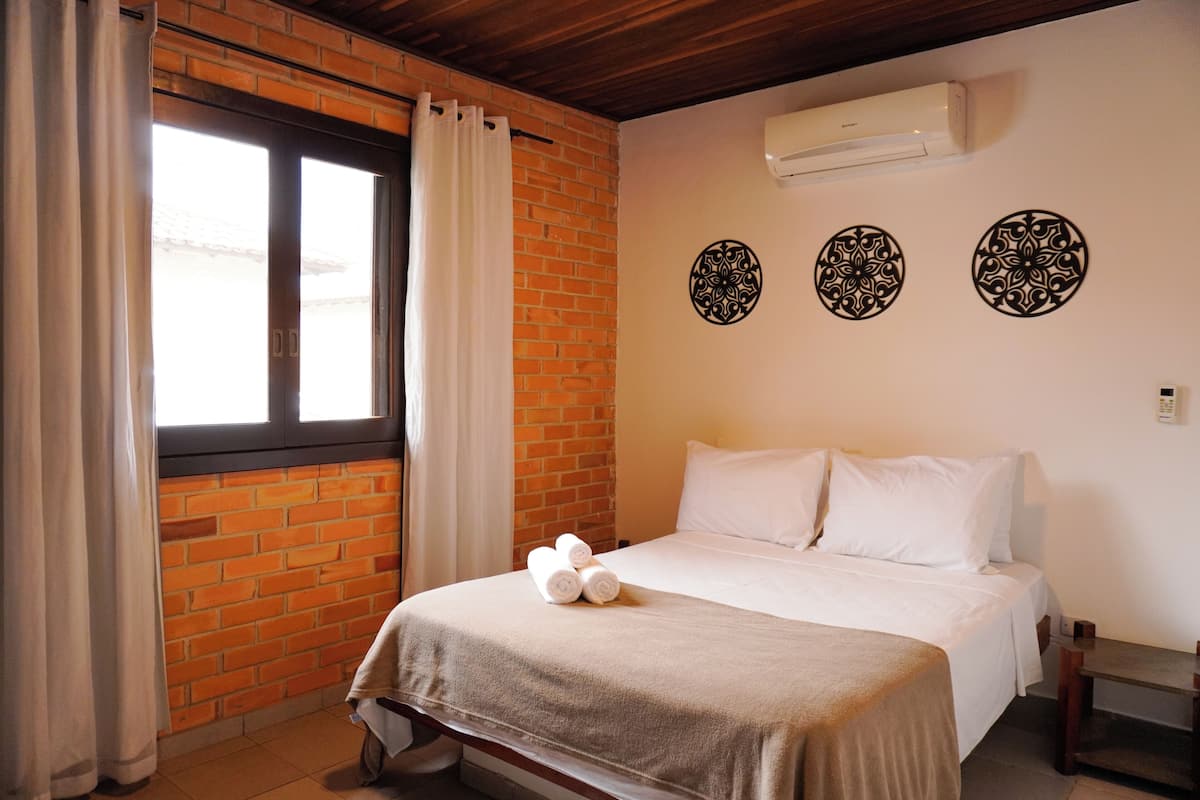 Ein Hotelzimmer mit Backsteinwand, einem Bett mit weißer Bettwäsche und Wanddekoration.