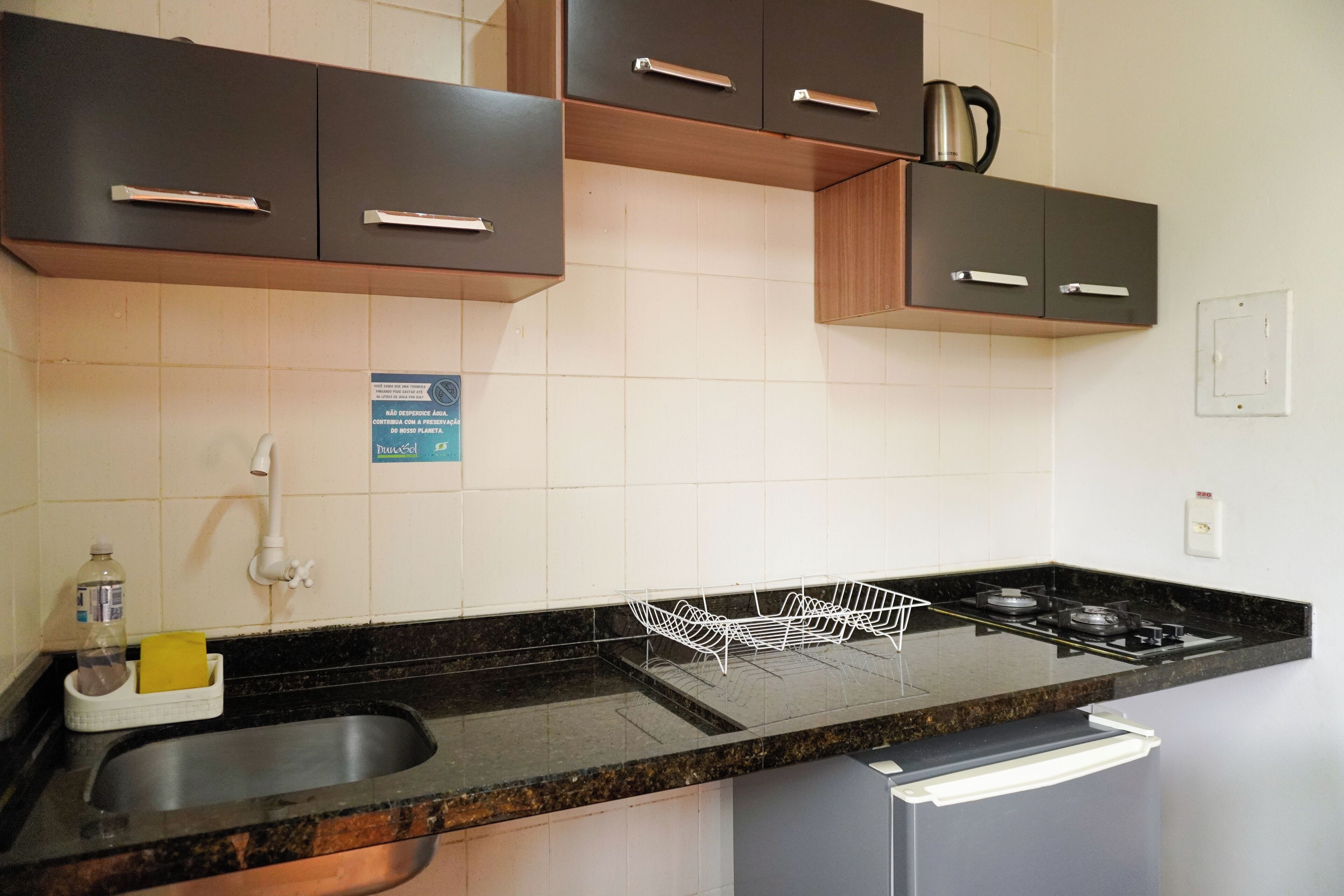 A modern kitchen with dark cabinets, a stainless steel sink, and a gas stove.