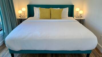 A neatly made bed with white bedding and a teal headboard, flanked by two bedside tables with lamps.