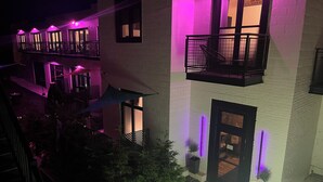 A multi-story building with balconies, a covered outdoor seating area, and a well-lit entrance. - The Factory (Beacon)