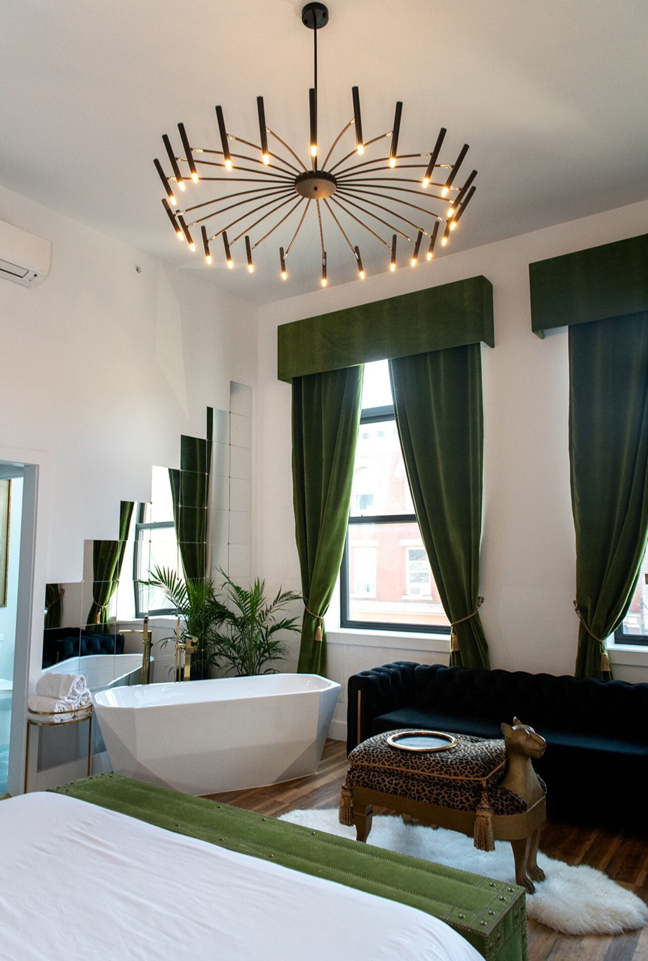 Un baño moderno con una bañera independiente, un espejo y una cortina verde.