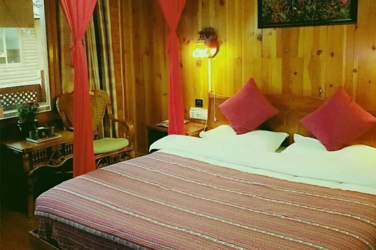 Une pièce en bois avec un lit, une chaise, une table de chevet et une lampe.