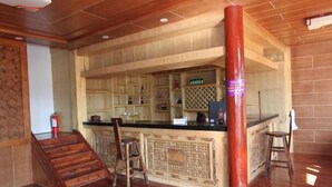 Un espace bar avec des étagères en bois, un comptoir et des tabourets.