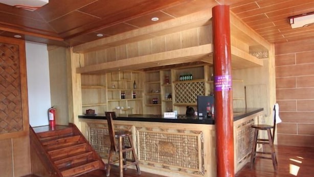 A bar area with wooden shelves, a counter, and stools. - Lugu Lake Zhenmeilige Hostel (Ninglang)
