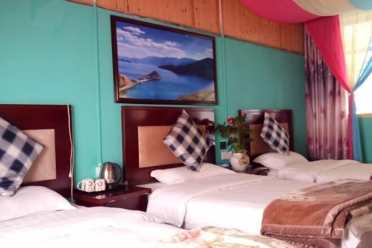Une chambre d’hôtel avec deux lits, un grand tableau représentant un paysage côtier et une fenêtre avec des rideaux.
