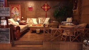 Een klassieke kamer met een zithoek, een tafeltje met een theepot, en een decoratieve wandversiering.