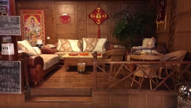 Une pièce à l’ambiance traditionnelle, avec un ensemble de canapés, une petite table sur laquelle est posée une théière, et une décoration murale.