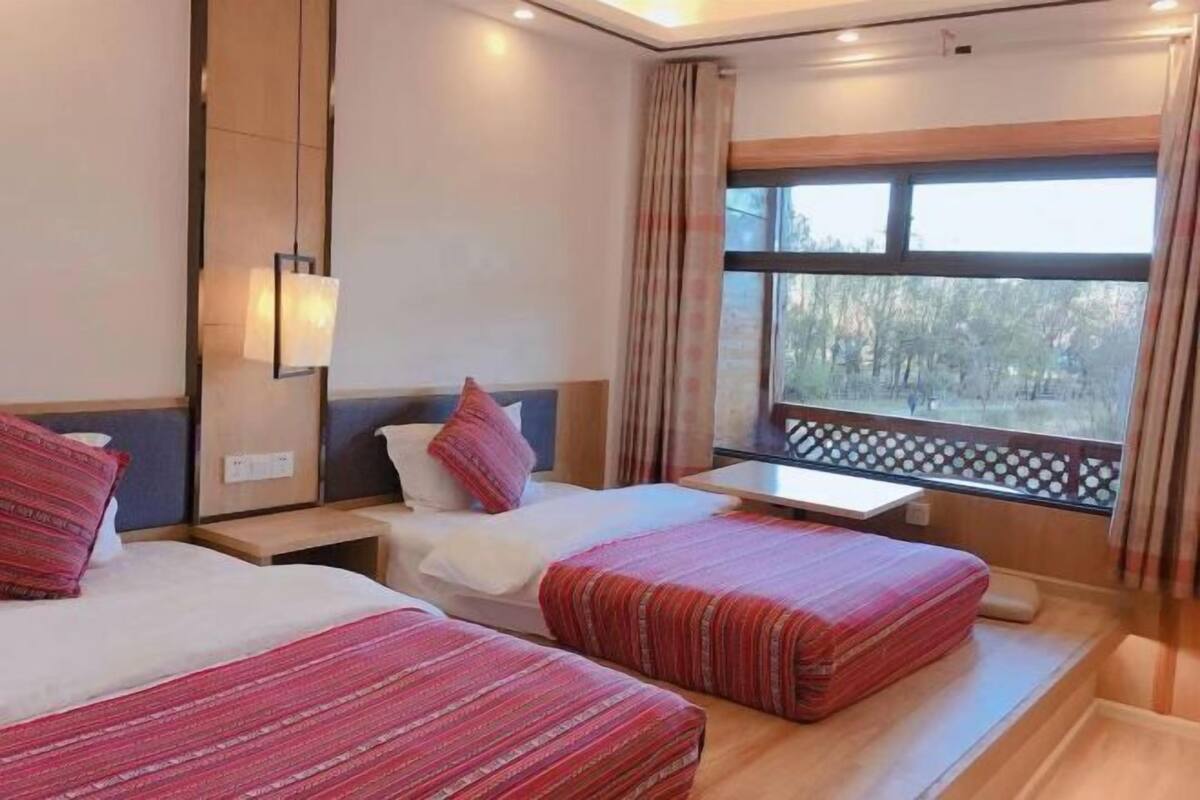 Une chambre d’hôtel avec deux lits, une fenêtre donnant sur un beau paysage et une petite table.