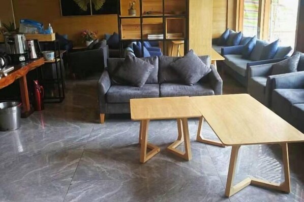 A modern living room with a grey sofa, a wooden coffee table, and a bookshelf.