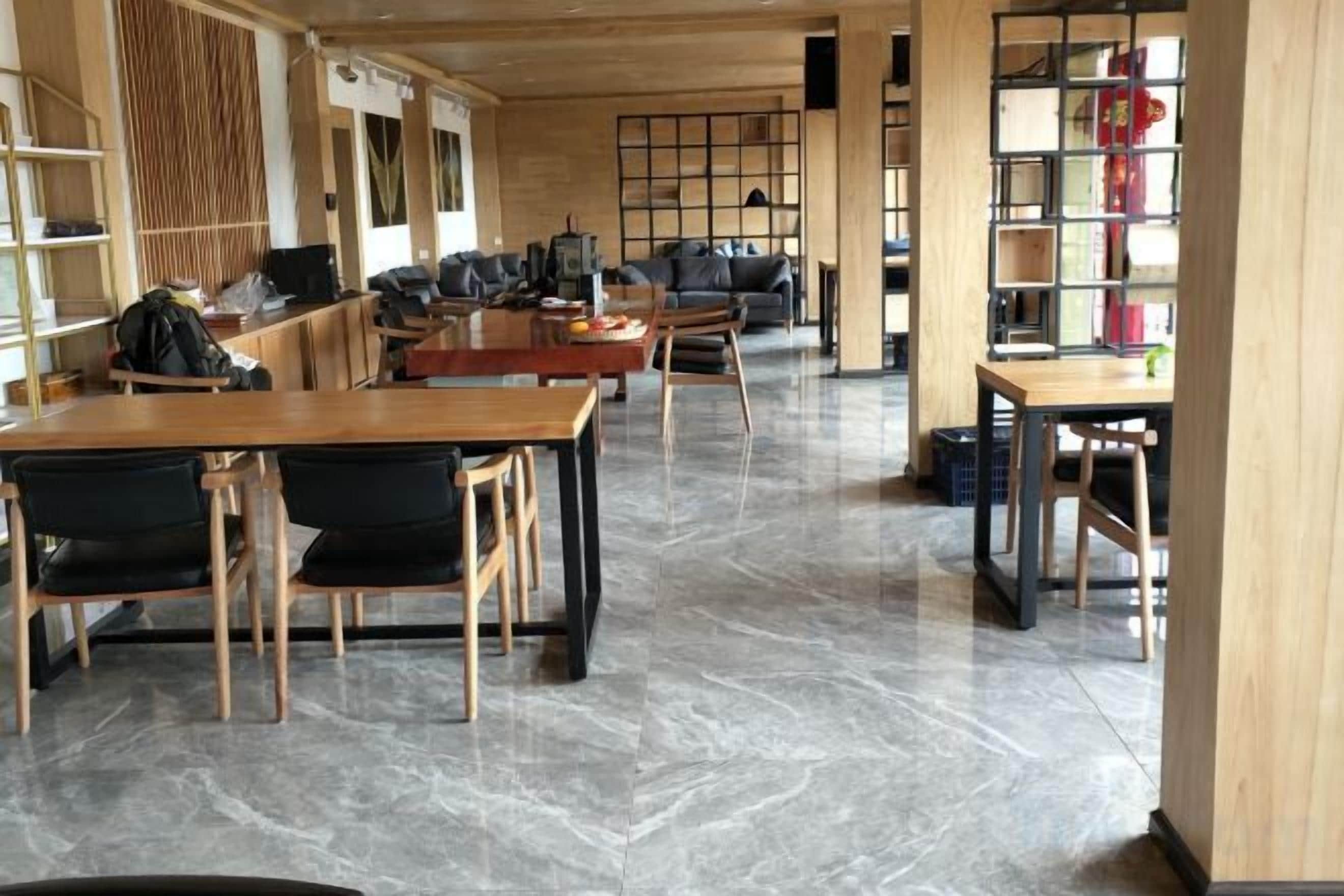 Une pièce spacieuse avec une table et des chaises en bois, une bibliothèque et un bureau avec un ordinateur.