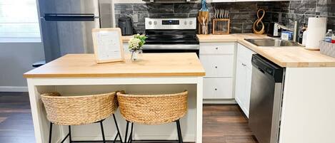 A compact kitchen with a central island, stainless steel appliances, and a dishwasher.